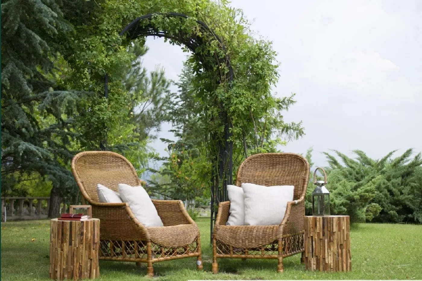 Outdoor garden lounge at VAAS Aspire low-rise floors with wicker seating, wooden side tables, and a pergola set amid lush greenery